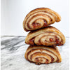 Raspberry Rugelach, flakey pastry swirled with raspberry filling, three pieces stacked and coated with cinnamon sugar.