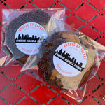 two chinese marble cookies with chocolate sprinkles, the cookie is thick and half brownie and half cookie, like a brookie placed on a red table with Noshes by Sherri labeling